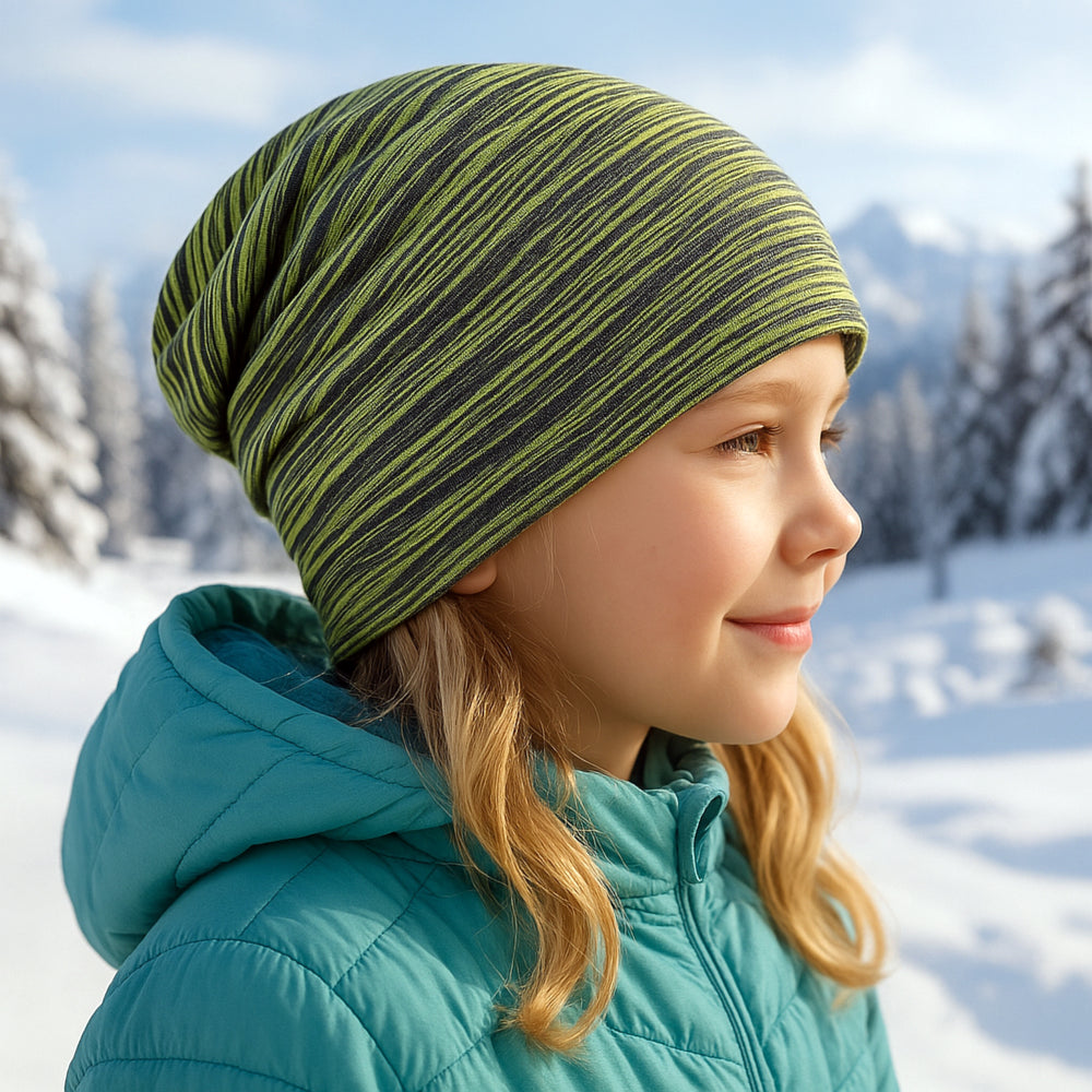Mädchen trägt Wollhuhn Öko Long Beanie, Wendemütze aus zweilagigem Baumwolljersey im Schnee. Hält Ohren warm, ideal für Kinder und Jugendliche, ganzjährig tragbar.