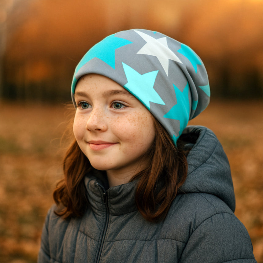 Junges Mädchen trägt Wollhuhn Öko Long Beanie mit großen Sternen, passend für Herbst, aus weichem, dehnbarem Baumwolljersey, ideal für kühle Tage.