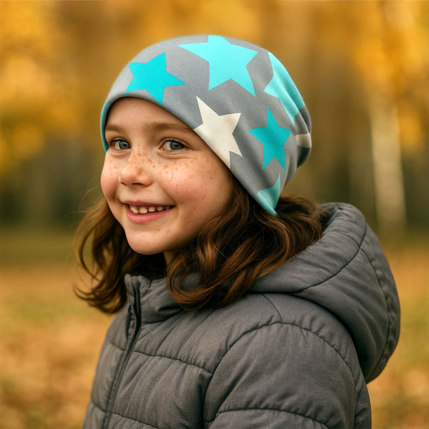 Mädchen in Wollhuhn Öko Long Beanie, zweilagig mit grauem und mintfarbenem Sternenmuster, ideal für Übergangszeit, warm und komfortabel für Kinder.