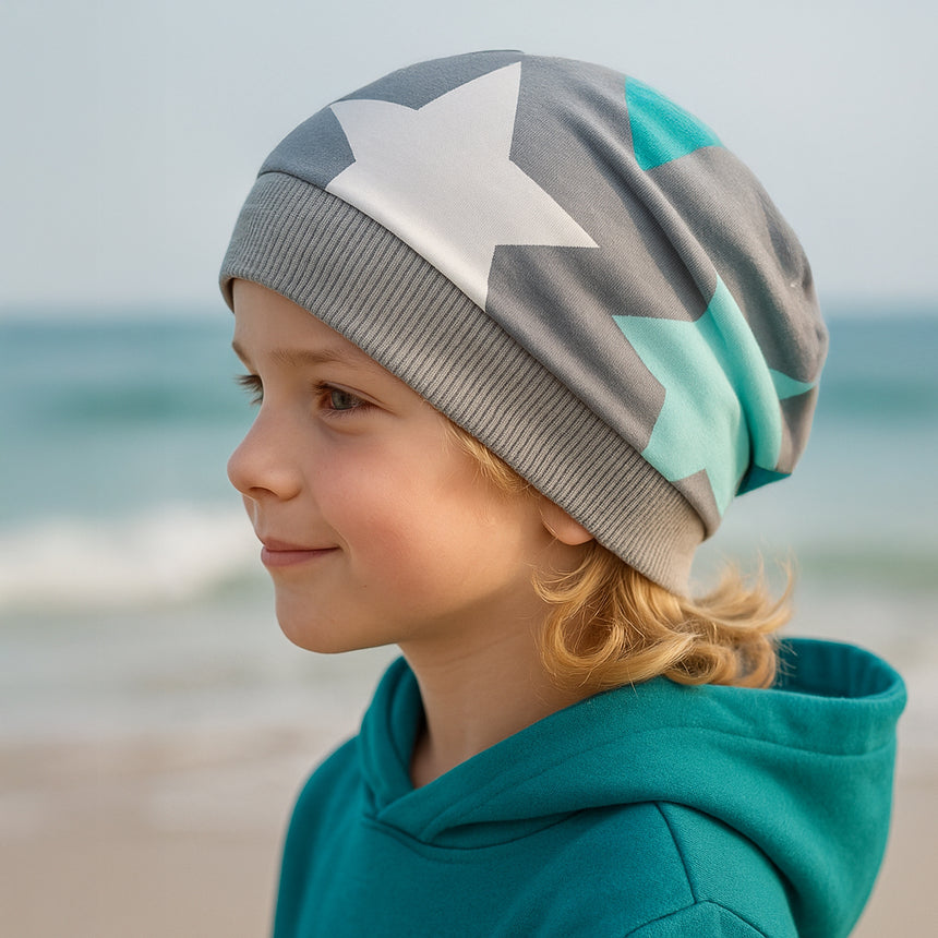 Kind am Strand mit Wollhuhn Dünne Öko Beanie-Mütze Sommer/Übergang Einlagig Big Stars Sterne Grau/Mint, handgemacht aus dehnbarem Öko-Jersey, ideal für kühle Tage.