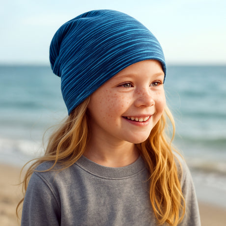Mädchen lächelt und trägt eine Wollhuhn Öko Long Beanie, Wendemütze, zweilagig, ideal für ganzjähriges Tragen, handgefertigt in Deutschland aus weichem Baumwolljersey.
