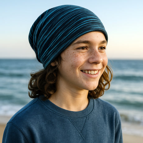 Junge am Strand mit Wollhuhn Öko Long Beanie, zweilagig und wendbar, ideal für Komfort das ganze Jahr über. Perfekt für Kinder und Jugendliche.