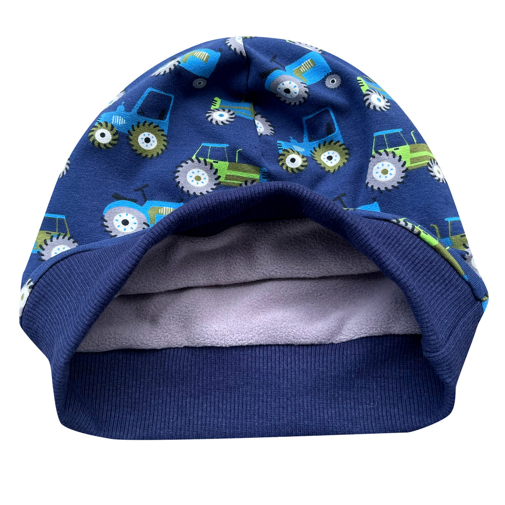 Wollhuhn ADD-ON Fleece-Futter für die Dünnen Beanies zeigt blaue Mütze mit Traktor-Designs, geeignet für zusätzliche Wärme durch eingenähtes Öko-Sportfleece.
