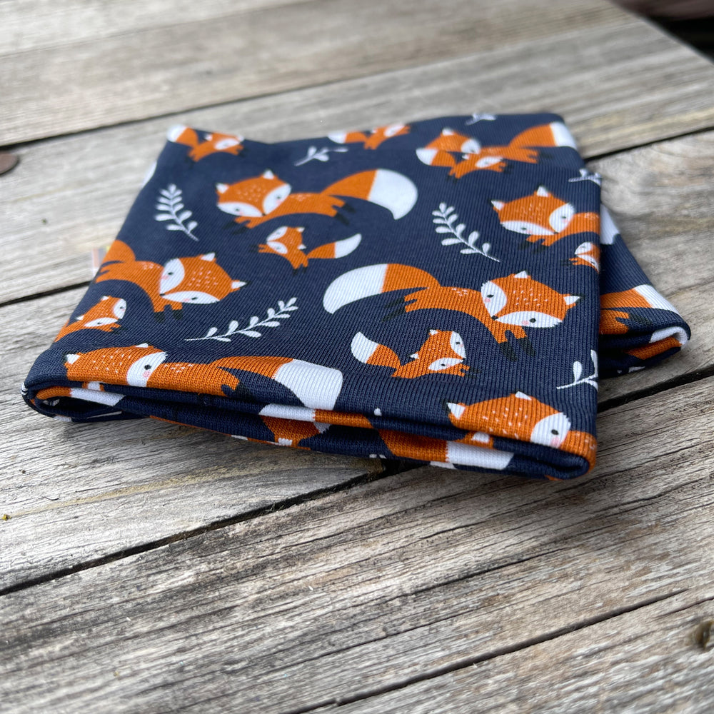 Wollhuhn Elastisches Öko Stirnband, zweilagig, mit Fuchs-Muster, auf Holztisch präsentiert. Handgemacht aus Bio-Baumwolle, ideal für alle Altersgruppen.