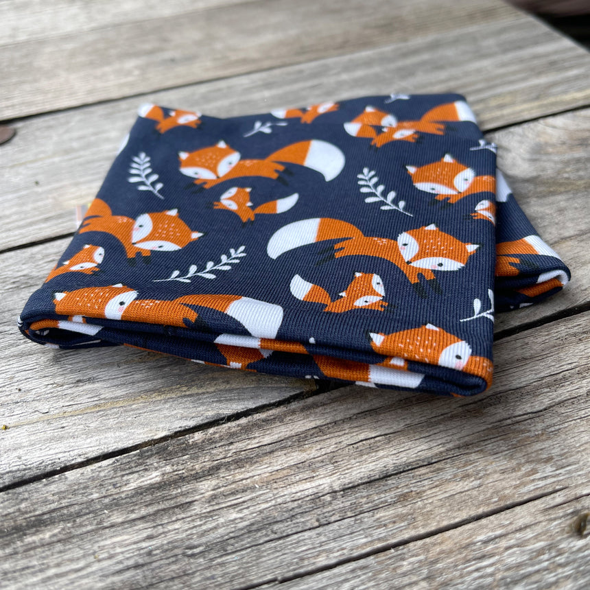 Wollhuhn Elastisches Öko Stirnband, zweilagig, mit Fuchs-Muster, auf Holztisch präsentiert. Handgemacht aus Bio-Baumwolle, ideal für alle Altersgruppen.