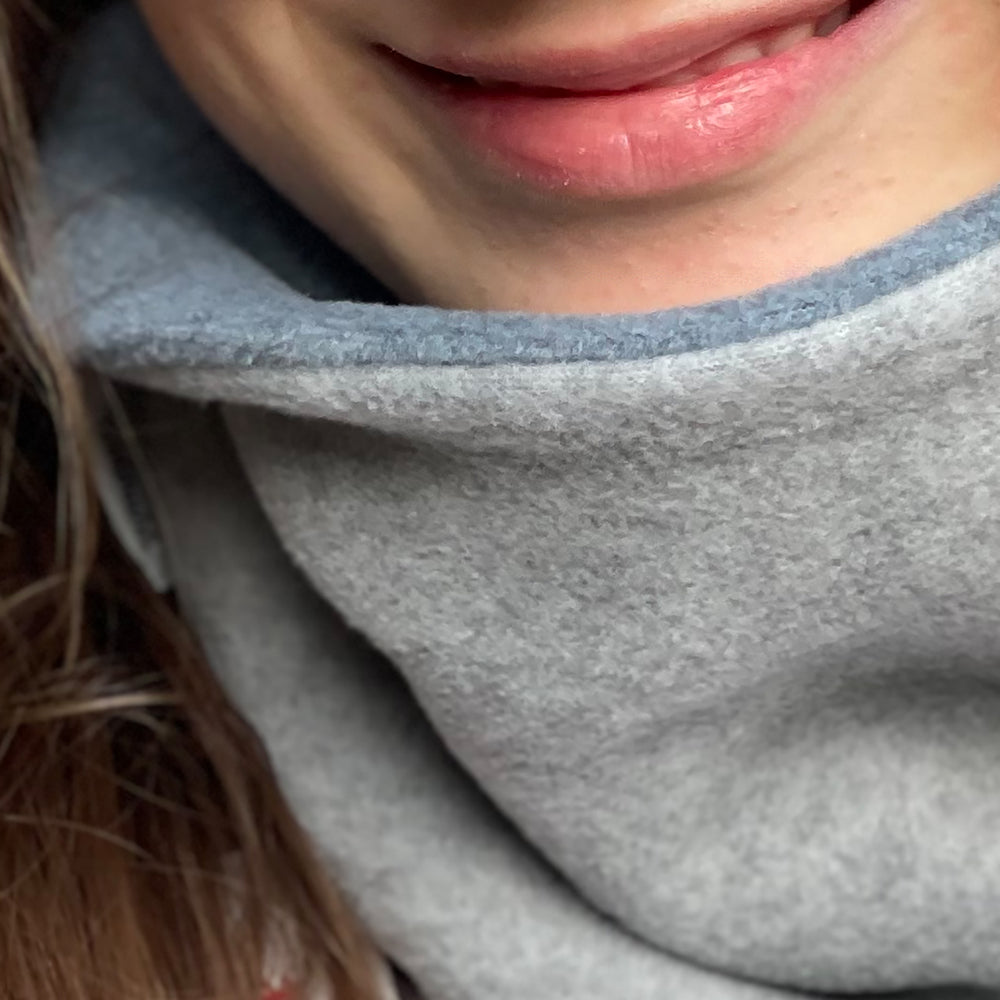 Nahaufnahme eines lächelnden Mundes, der den Wollhuhn WINTER Halstuch/Schlupfschal „Unser Wärmster“ präsentiert, handgefertigt aus doppellagigem Fleece für optimalen Kälteschutz.