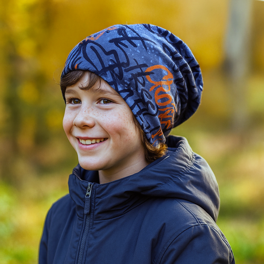 Ein Junge trägt eine Wollhuhn Öko Long Beanie / Wendemütze, Ganzjährig, Zweilagig, Skater Grau/Orange im Herbstpark. Ideal für Komfort und Wärme.