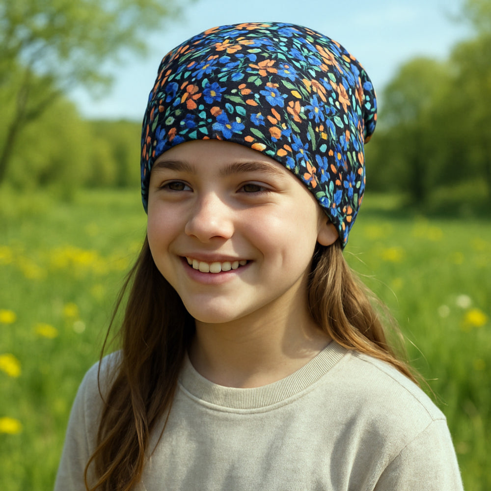 Mädchen trägt Wollhuhn Öko Shorties, zweilagige Wendemütze, stilvoll in Blumen Schwarz/Bunt, perfekt für aktive Kinder, handgefertigt in Deutschland.