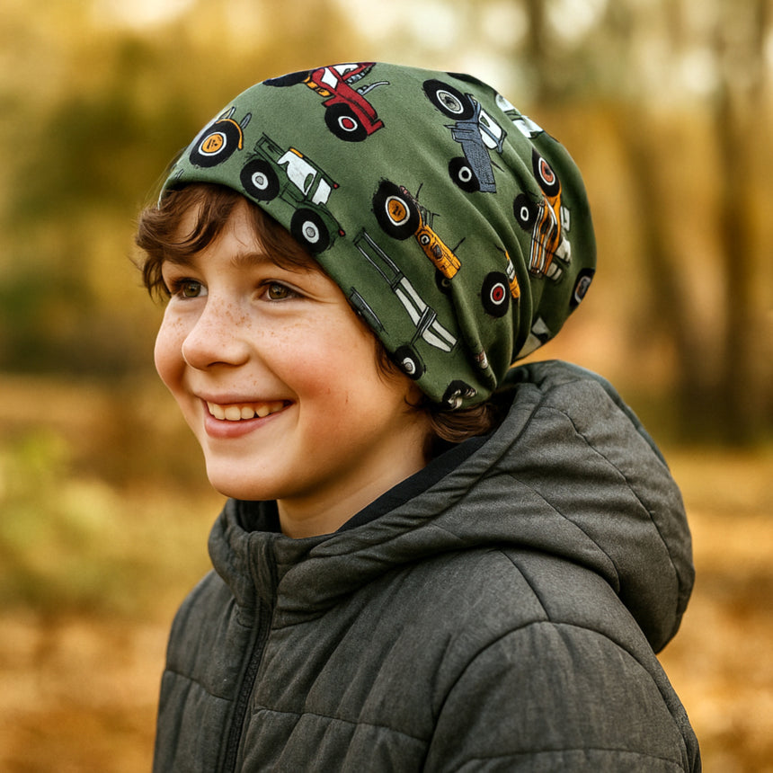 Junge trägt Wollhuhn Öko Long Beanie, zweilagig, mit Traktormuster in grün. Ideal für Herbst/Winter, angenehm und wendbar, handgefertigt in Deutschland.