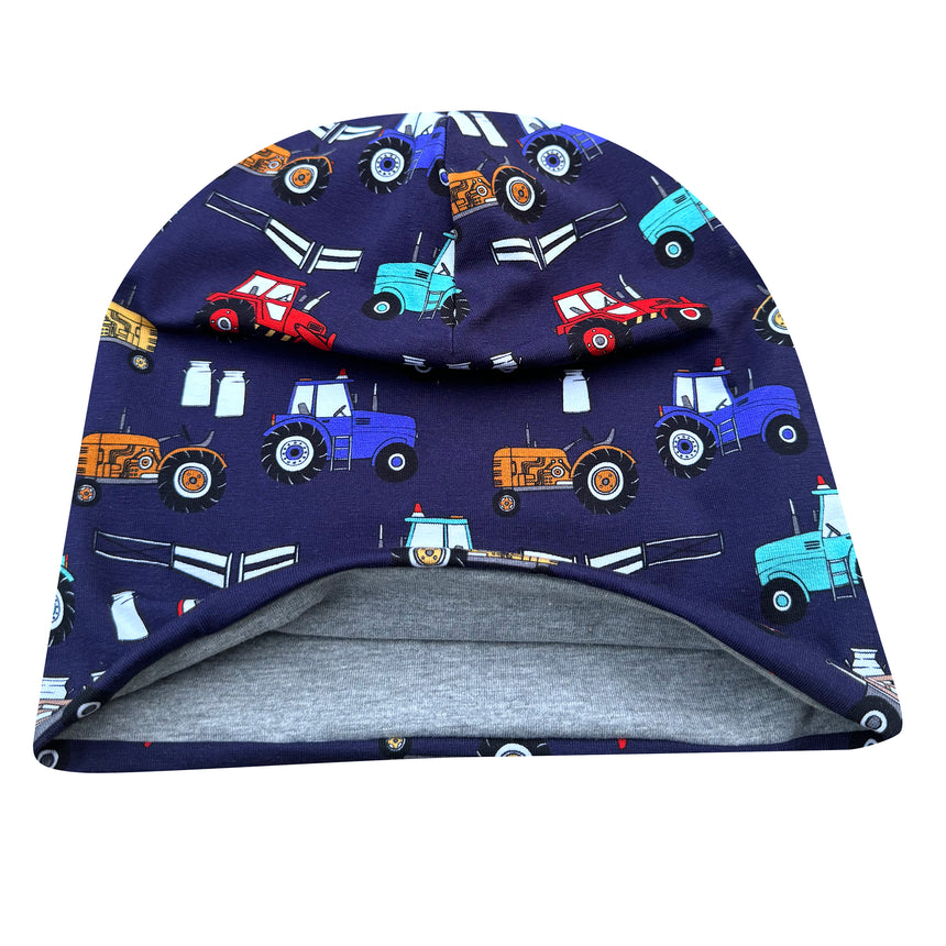 Wollhuhn Öko Long Beanie: Weiche, zweilagige Wendemütze mit bunten Traktoren auf navyblauem Hintergrund, innen hellgrau. Ideal für Kinder, bietet bequemen, lockeren Sitz.