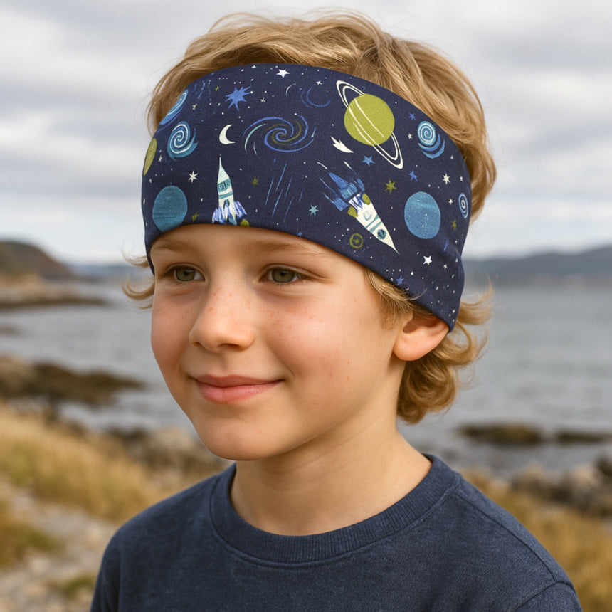 Junge trägt Wollhuhn Elastisches Öko Stirnband Jersey Zweilagig Breit Space/Rakete Dunkelblau, ideal für Outdoor-Aktivitäten, handgemacht aus Bio-Baumwolle.