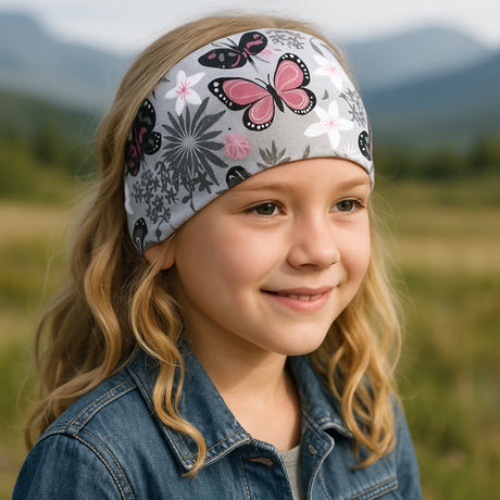 Mädchen trägt Wollhuhn Elastisches Öko Stirnband aus Jersey, zweilagig und breit, mit Schmetterlingsmotiv in Grau/Rosa. Ideal für Alltag und Outdoor-Aktivitäten.