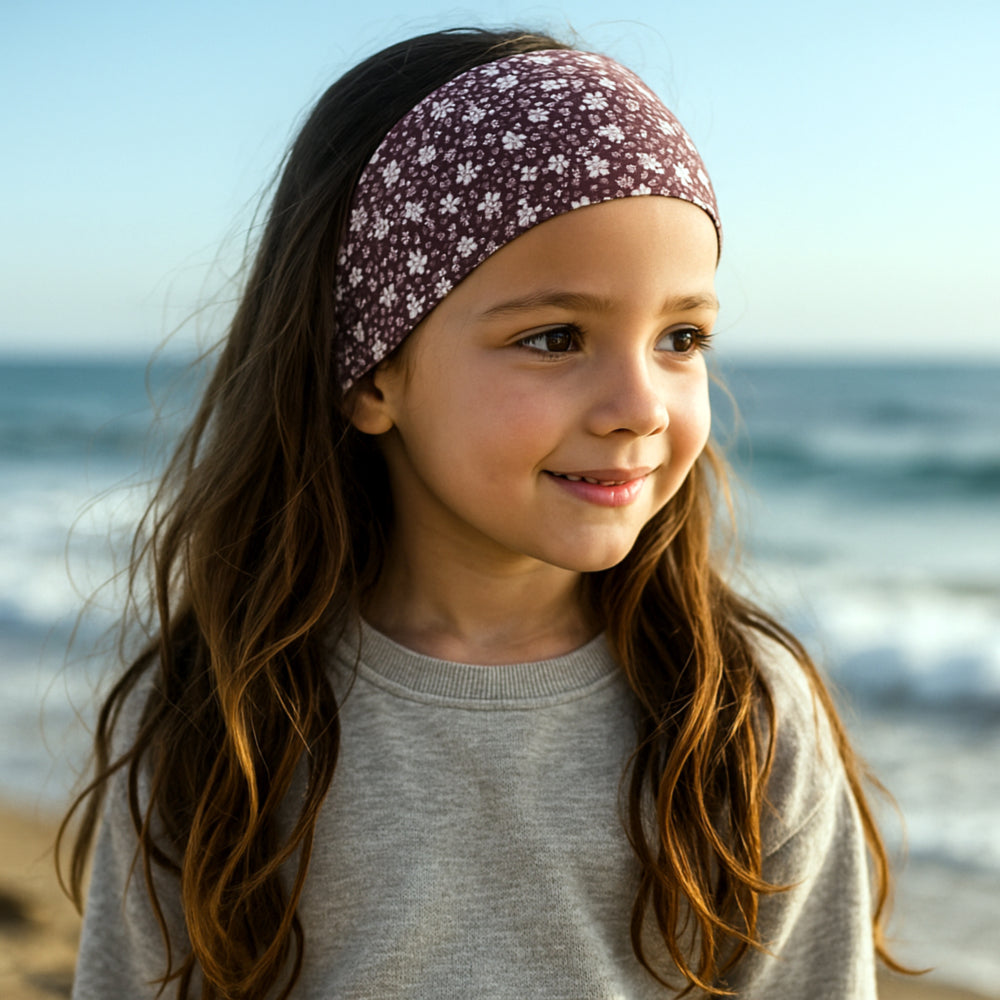 Nahaufnahme eines Gesichts, das ein Wollhuhn Elastisches Öko Stirnband / Haarband Jersey Zweilagig Breit Blümchen Mauve trägt, ideal für Outdoor-Aktivitäten.