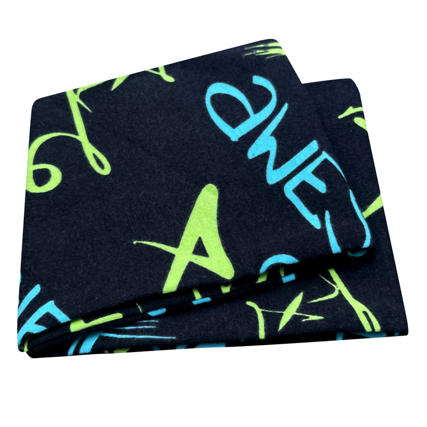 Wollhuhn Elastisches Öko Stirnband, handgefertigt, schwarz mit blauen und grünen Buchstaben, ideal für vielseitige Nutzung, aus weicher, zertifizierter Bio-Baumwolle.