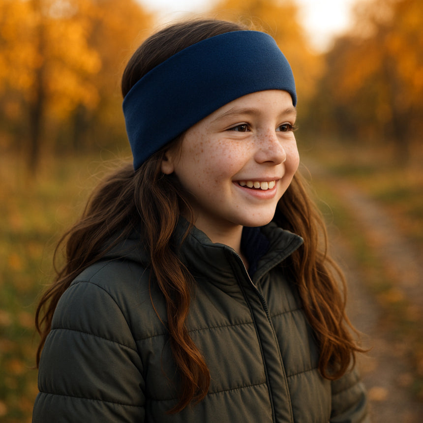 Mädchen trägt Wollhuhn Elastisches Öko Stirnband SPORTFLEECE, zweilagig, royalblau, im Herbstwald. Hält Ohren warm, ideal für kalte Tage. Handgemacht in Deutschland.