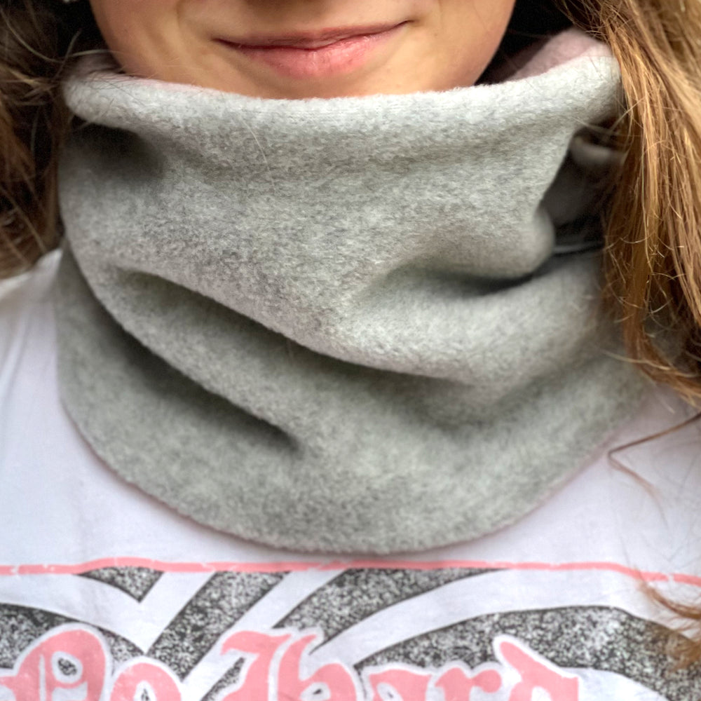 Frau trägt Wollhuhn WINTER Halstuch/Schlupfschal „Unser Wärmster“ aus zwei Lagen Fleece in Hellgrau/Rosa, handgemacht und ideal für kalte Tage.