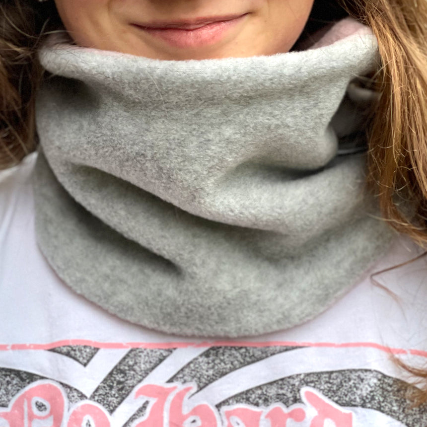 Frau trägt Wollhuhn WINTER Halstuch/Schlupfschal „Unser Wärmster“ aus zwei Lagen Fleece in Hellgrau/Rosa, handgemacht und ideal für kalte Tage.