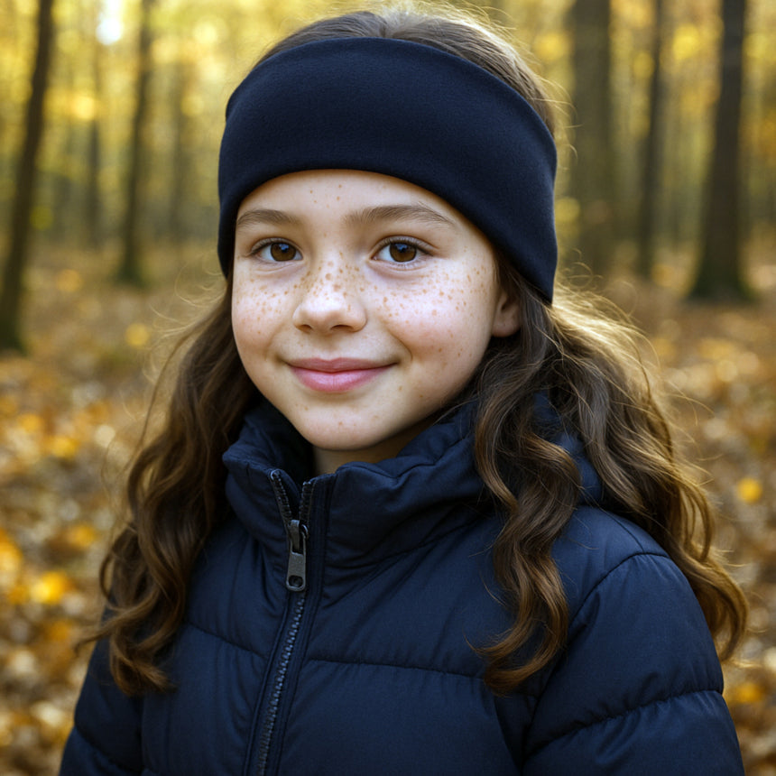 Mädchen im Wald mit Wollhuhn Stirnband aus dunkelblauem Sportfleece, zweilagig und windabweisend, ideal für kalte Herbsttage.