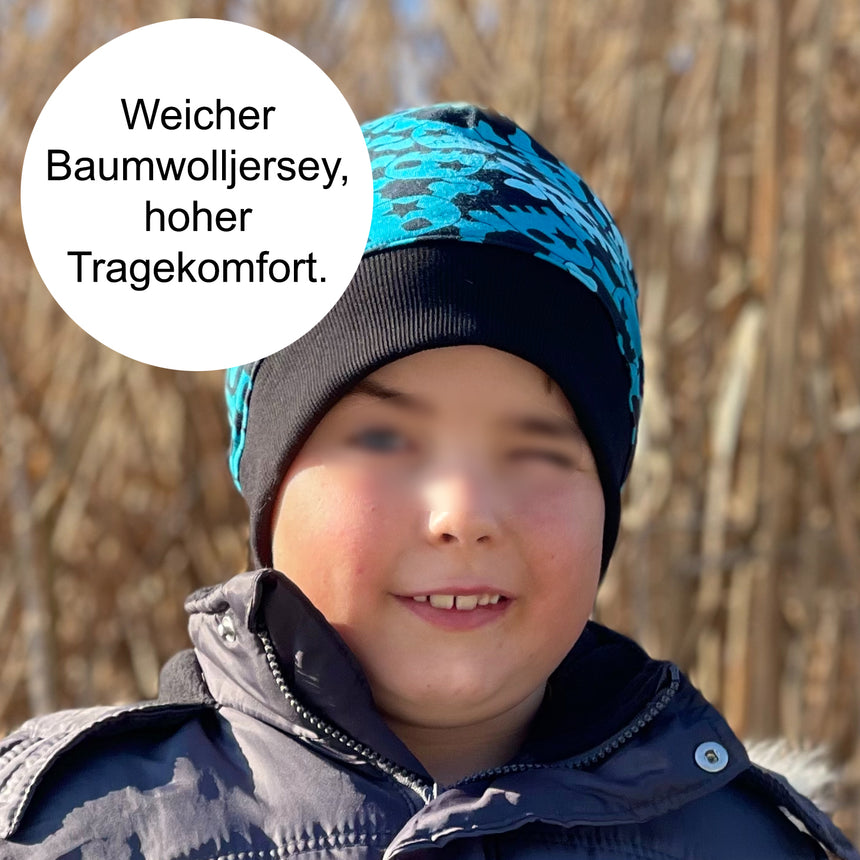 Junge trägt Wollhuhn Dünne Öko Beanie-Mütze, handgemacht aus elastischem Öko-Jersey, perfekt für Übergangszeit, bequem unter Helmen tragbar.
