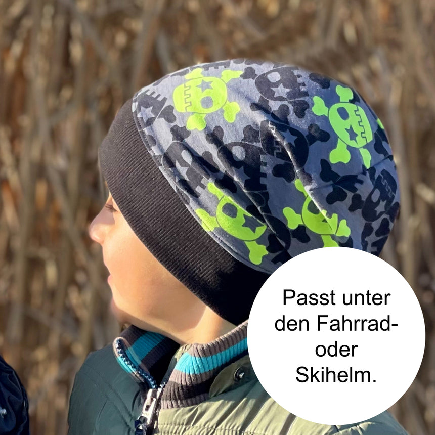 Kind trägt Wollhuhn Dünne Öko Beanie-Mütze, ideal für Sommer/Übergang, handgemacht aus elastischem Öko-Jersey, bequem unter Helmen zu tragen.