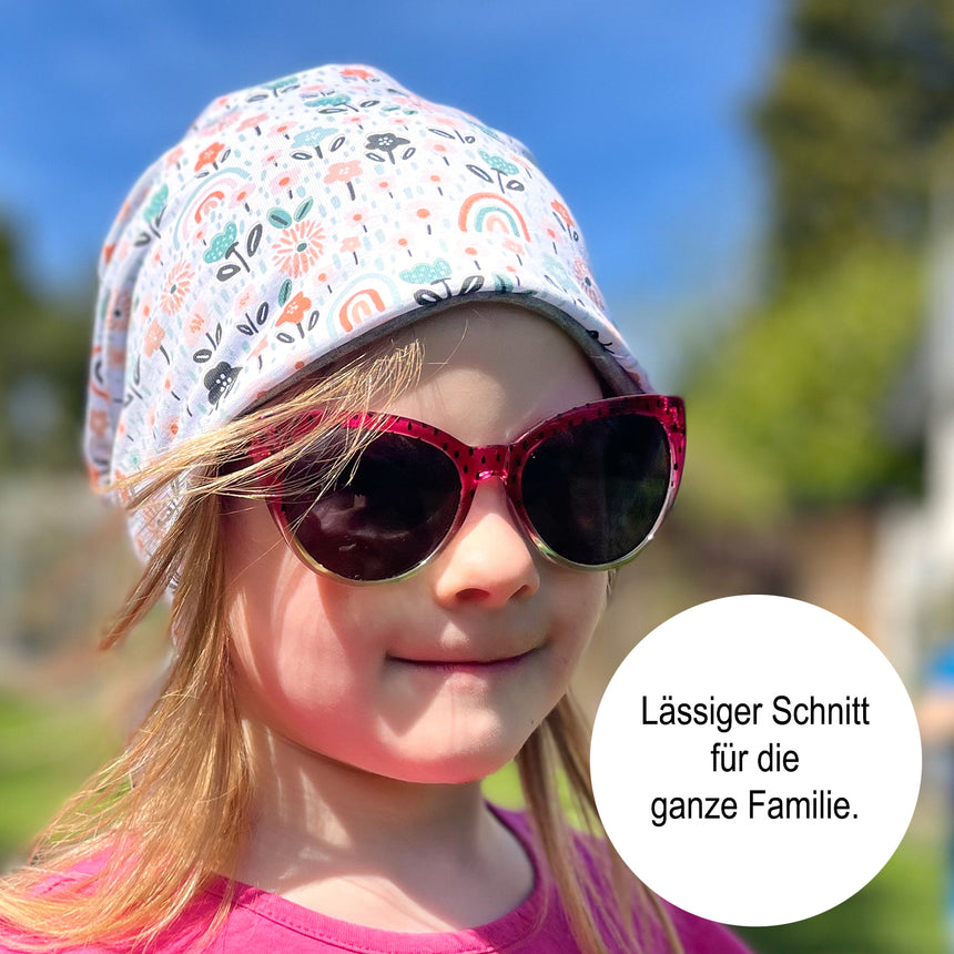 Mädchen trägt Wollhuhn Öko Long Beanie / Wendemütze, Pony Blau, aus weichem Baumwolljersey, zweilagig für ganzjähriges Tragen. Ideal für Komfort und Stil.