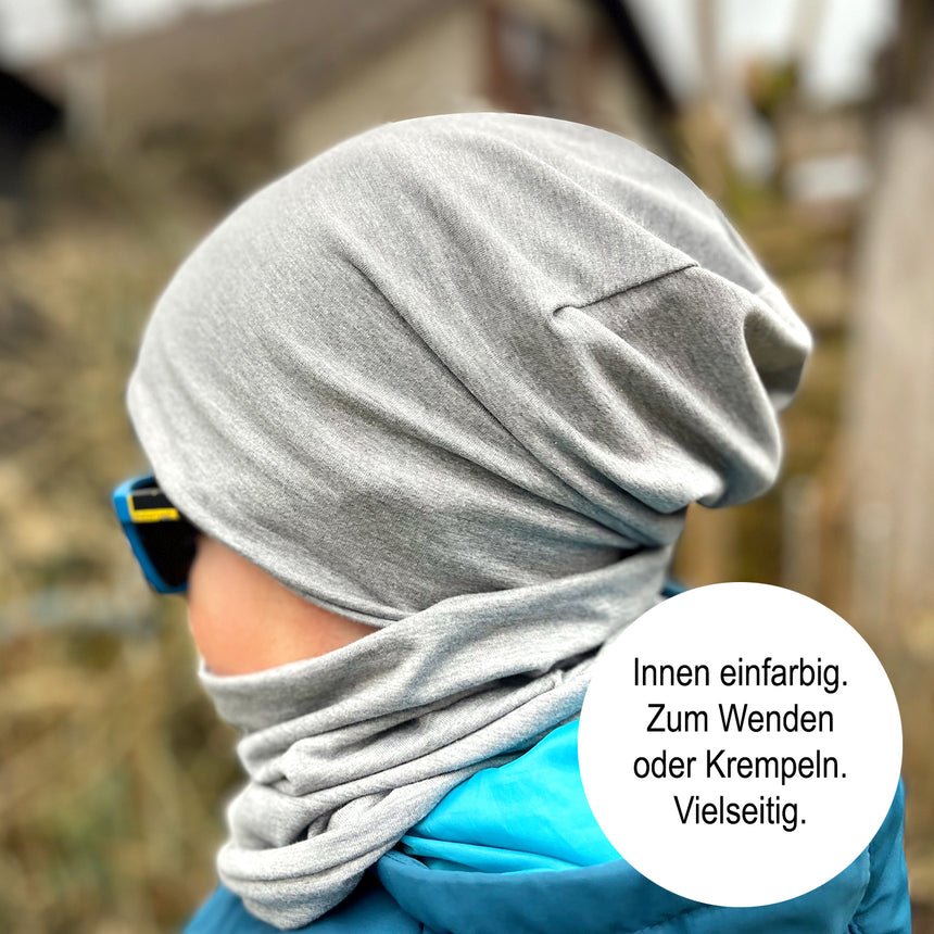 Person trägt Wollhuhn Öko Long Beanie als Wendemütze, zweilagig und bequem aus Baumwolljersey. Ideal für Herbst und Winter, stilvoll und funktional.