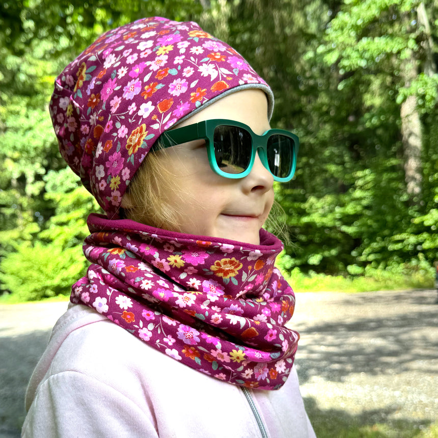 Mädchen trägt Wollhuhn Öko Shorties, Wendemütze, zweilagig, Blumen Beere. Handgemacht, stilvoll, bequem. Perfekt für aktive Kinder und Teenager.