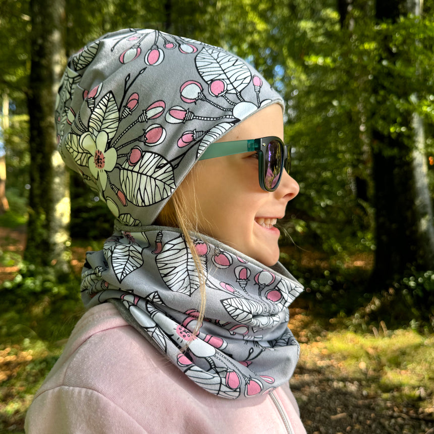 Mädchen mit Sonnenbrille und Wollhuhn Öko Shorties Wendemütze, zweilagig, ideal für aktive Kinder, handgefertigt in Deutschland, stilvoll und bequem.