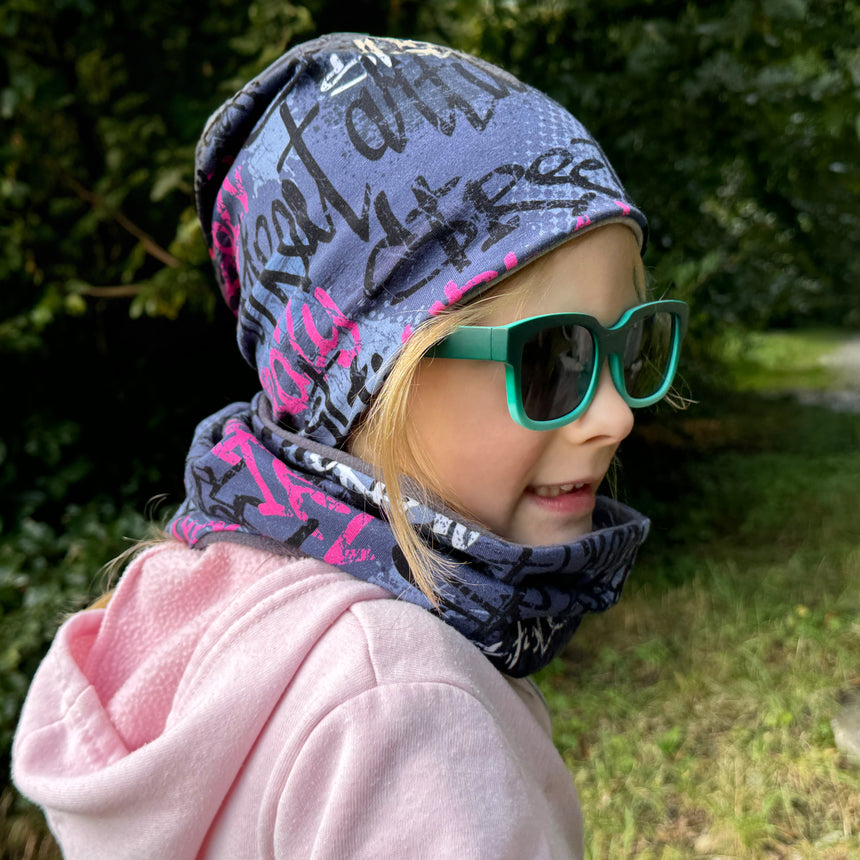 Mädchen mit Sonnenbrille trägt Wollhuhn Öko Long Beanie, Wendemütze; zeigt die lässige Passform und Vielseitigkeit des zweilagigen, handgefertigten Designs aus Oberschwaben.