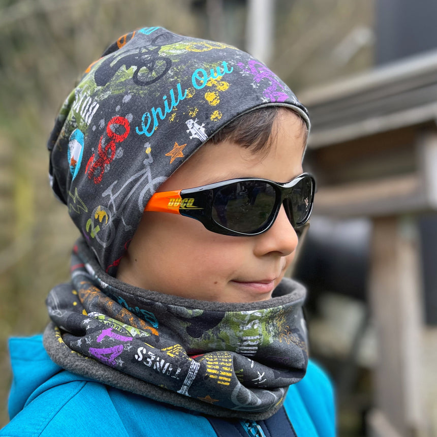 Junge mit Wollhuhn Öko Shorties Wendemütze, Ganzjährig, Zweilagig. Trägt stylische, handgemachte Mütze aus Öko-Jersey, ideal für aktive Kinder.