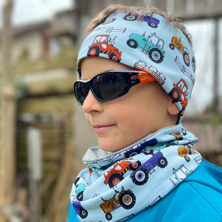 Junge trägt Wollhuhn Elastisches Öko Stirnband/Haarband, Jersey zweilagig, mit Traktor-Motiv. Handgemacht, weich, vielseitig, ideal für Outdoor-Aktivitäten.