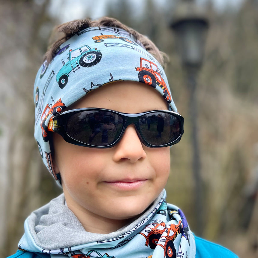 Junge mit Sonnenbrille und Bandana trägt das Wollhuhn Elastische Öko Stirnband/Haarband, handgemacht aus weichem Jersey, geeignet für diverse Aktivitäten.