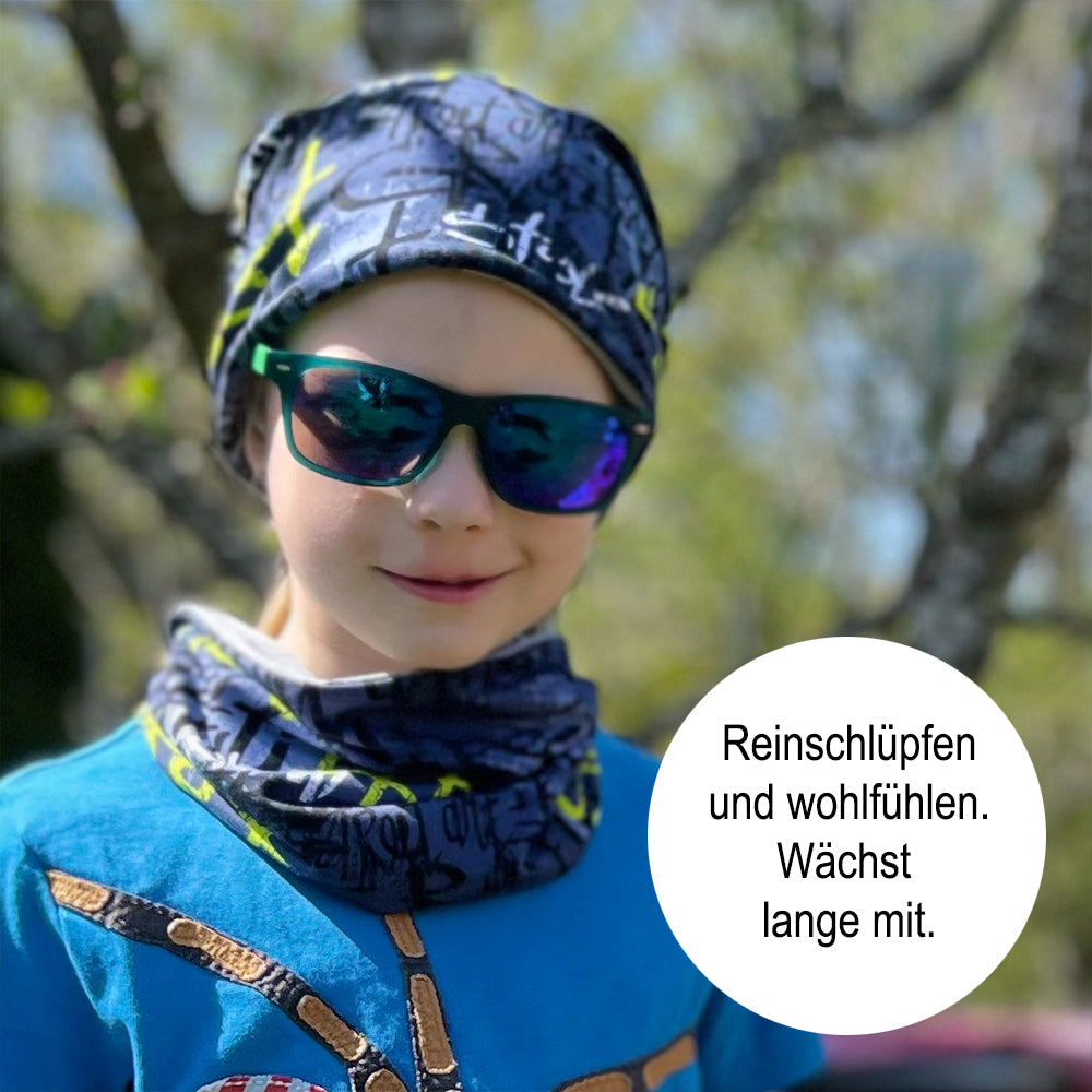 Kind mit Sonnenbrille trägt Wollhuhn Leichtes Lockeres Öko Jersey Halstuch, ideal für Übergangszeiten, handgefertigt in Deutschland, weich und einfach anzuziehen.