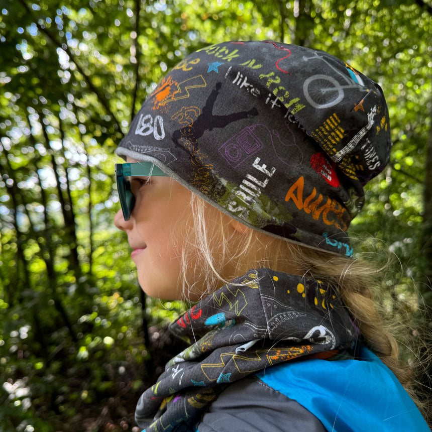 Mädchen mit Wollhuhn Öko Shorties Wendemütze, stilvoll mit Sonnenbrille und Schal, ideal für aktive Kinder, handgefertigt in Deutschland.