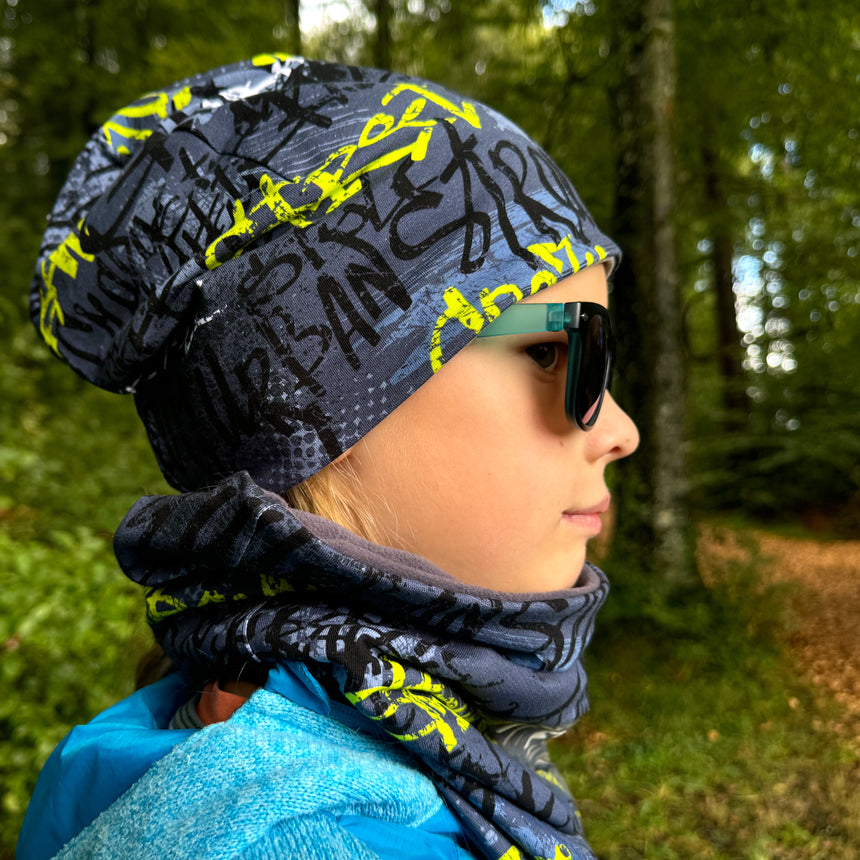 Frau trägt Wollhuhn Öko Shorties Beanie, Wendemütze, stilvoll und bequem, handgefertigt aus Öko-Jersey, ideal für Freizeitaktivitäten und unter Helmen.