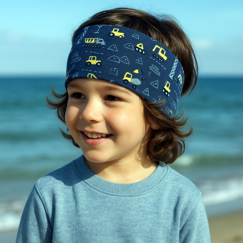 Kind am Strand trägt das Wollhuhn Elastisches Öko Stirnband, handgemacht und zweilagig, ideal für vielseitige Outdoor-Aktivitäten. Perfekt für empfindliche Haut und sportliche Abenteuer.