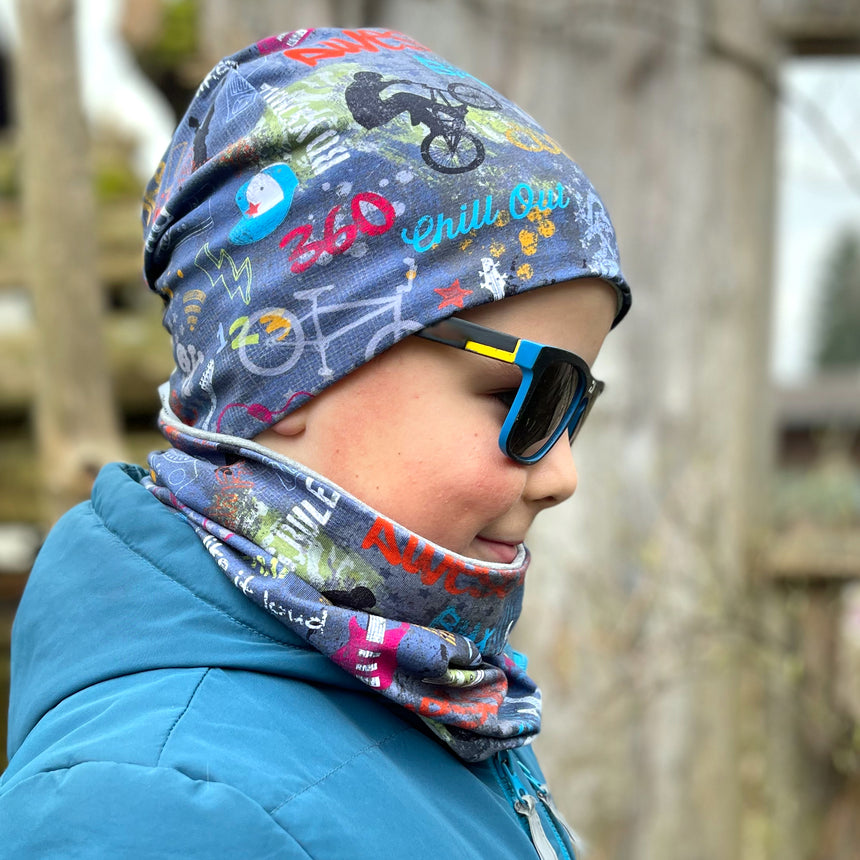 Ein Junge trägt Wollhuhn Öko Shorties, eine zweilagige Wendemütze aus Öko-Jersey, passend für aktive Kinder und Teenager.