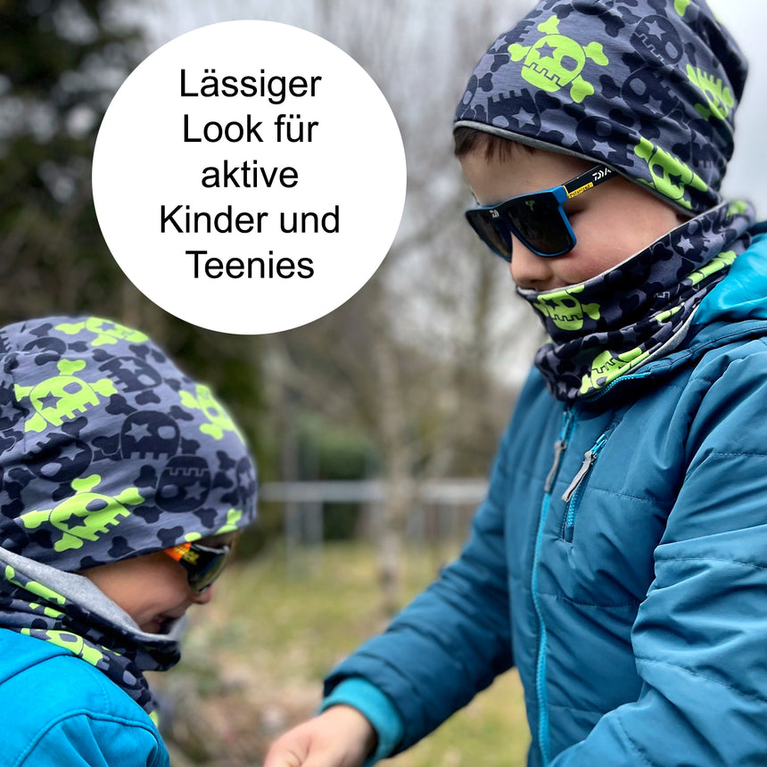 Jungen tragen Wollhuhn Öko Shorties, Wendemütze mit Totenkopfdesign. Handgefertigt, bequem, ideal für aktive Kinder, bietet Wärmeschutz und stilvolle Funktionalität.