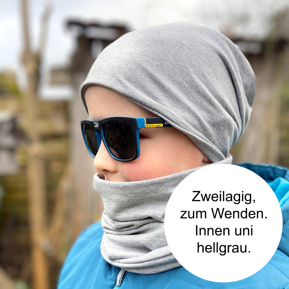 Junge trägt Wollhuhn Öko Shorties Wendemütze, zweilagig und bequem, mit Sonnenbrille und Schal, ideal für ganzjähriges Tragen.