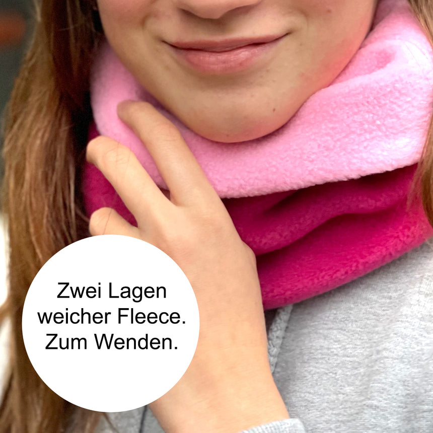 Frau trägt Wollhuhn WINTER Halstuch/Schlupfschal „Unser Wärmster“, doppellagiger Fleece, pink. Handgemacht, bequem und warm, ideal für kalte Tage.