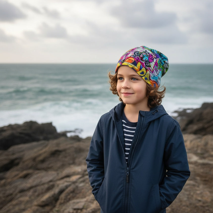 Kind am Meer mit Wollhuhn Öko Long Beanie, zweilagig, buntes Streetart-Design, bequem und formbeständig, perfekt für ganzjähriges Tragen.