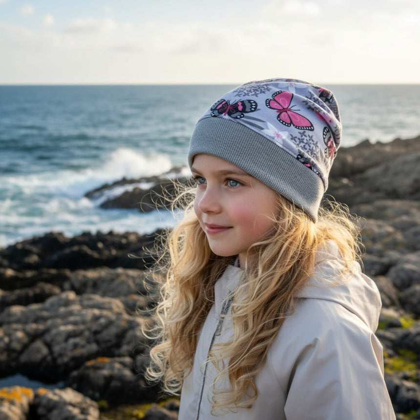 Mädchen trägt Wollhuhn Dünne Öko Beanie-Mütze mit Schmetterlingen, ideal für Übergangszeit, handgemacht aus Öko-Jersey, sitzt bequem und wächst mit.