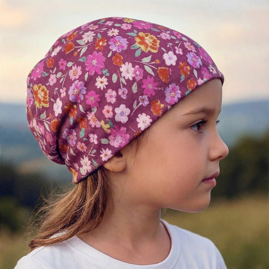 Kind mit Wollhuhn Öko Shorties Wendemütze, zweilagig, Blumenmuster. Handgemacht, bequem und mitwachsend, perfekt für aktive Kinder und Jugendliche.