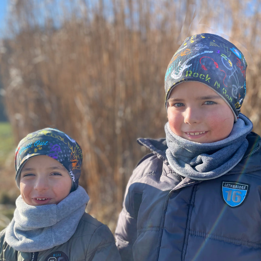 Zwei Kinder tragen Wollhuhn Öko Long Beanie Wendemützen, ideal für jede Jahreszeit und aus weichem Baumwolljersey gefertigt, perfekt für Komfort und Stil.