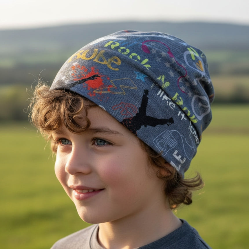 Junger Junge trägt Wollhuhn Öko Shorties, eine zweilagige, mitwachsende Wendemütze mit bunten Mustern, ideal für aktive Kinder und ganzjährig geeignet.