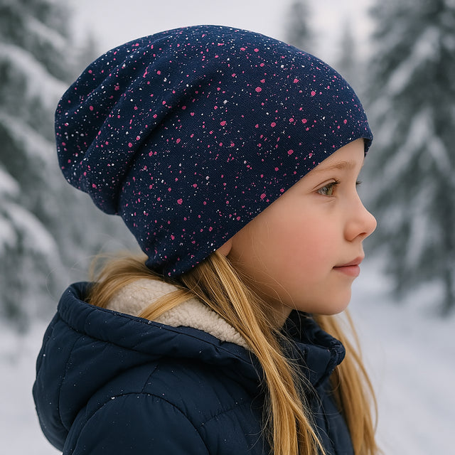 Wollhuhn Öko Long Beanie / Wendemütze auf einem Mädchen im Schnee, zeigt die lässige, bequeme Passform und zweilagige Jersey-Verarbeitung für kaltes Wetter.