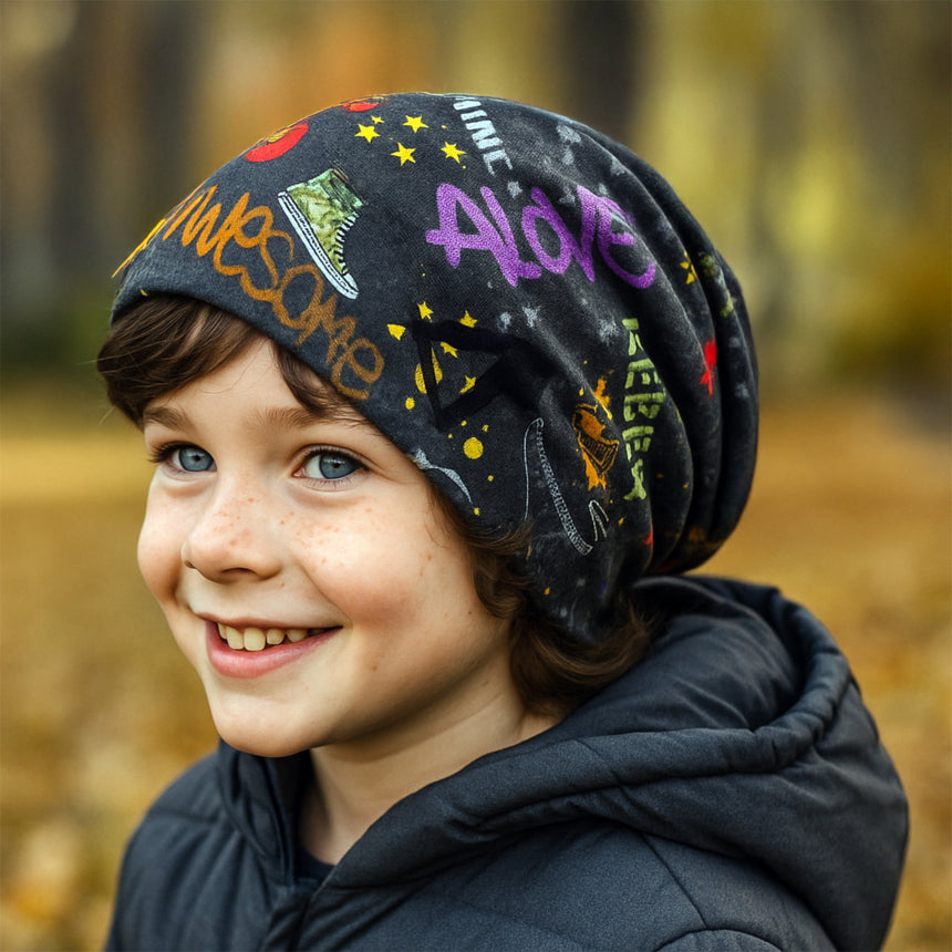 Junge mit Wollhuhn Öko Long Beanie, dunkelgrau, zweilagig, im Herbst. Slouchy Look, bunte Graffiti-Muster. Ideal für milde Tage, handgemacht in Deutschland.
