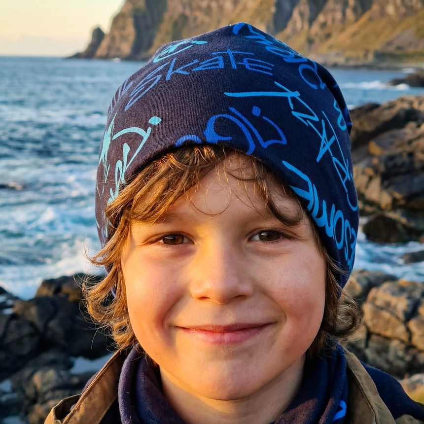 Junge mit Wollhuhn Öko Long Beanie am Meer, lässig getragen. Handgefertigt, zweilagig, ideal für Übergangszeiten, bietet stilvollen Komfort und Wärme.