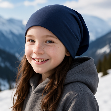 Mädchen im Schnee trägt Wollhuhn Öko Long Beanie, dunkelblau, aus weichem Öko-Jersey, lässig und wendbar, ideal für milde Winter und Freizeit.