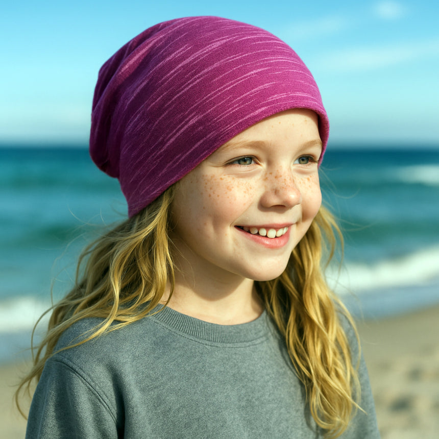 Mädchen am Strand trägt Wollhuhn Öko Long Beanie, Wendemütze, zweilagig und bequem, für ganzjährigen Gebrauch geeignet. Perfekt für das Wachstum von Kindern.
